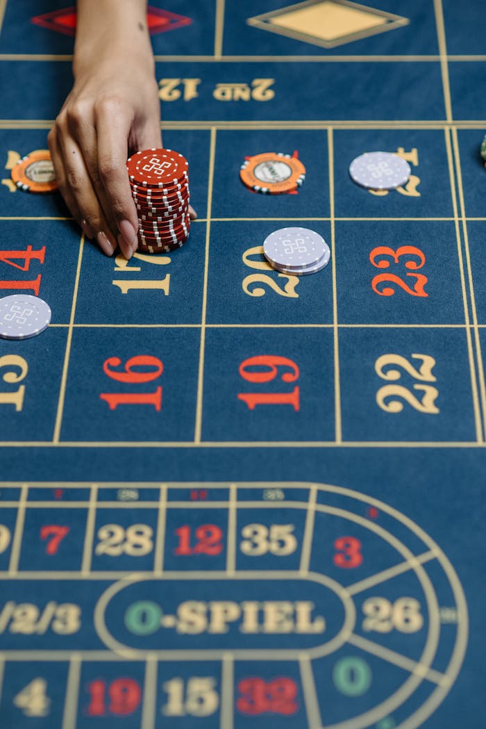 Close-up of a hand placing chips on a casino roulette table during a game.